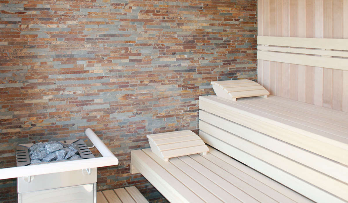 Sauna in Elementbauweise mit zwei Liegen und Steinmauer im Hintergrund